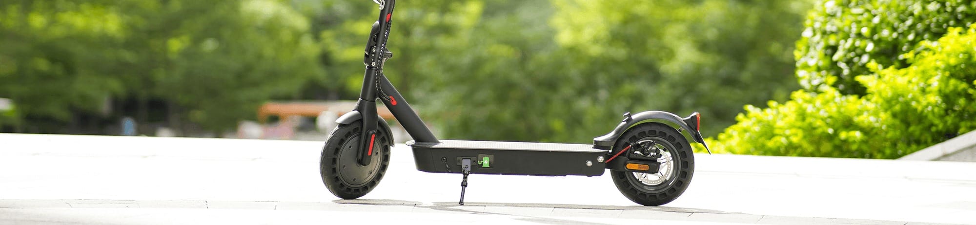 Piros és fekete elektromos roller, zöld háttér